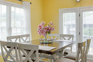 Orchid Arrangement on Wood Dining Table and Farmhouse Rustic Chairs in Yellow Dining Room