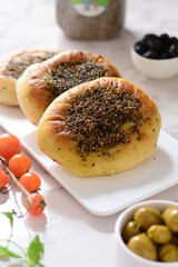 Traditional arabic food manaqish , Served in a white plate , with green olive , black olive , And cherry tomatoes