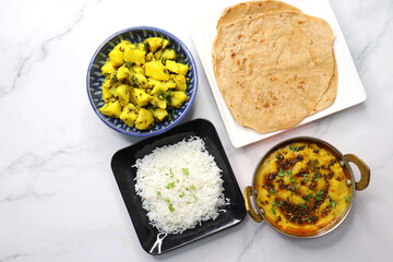 Indian simple homecooked meal aloo ki sabzi, roti, dal, chawal. Wholesome comfort food. vegetarian thali or Indian food with lentils, potato curry, rice and flat bread. copy space