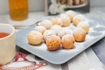 Round donuts in powdered sugar, curd donuts on a rectangular gray plate