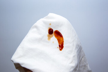 Tomato sauce spilled on white t shirt. Dirty food stain droplet on fabric.