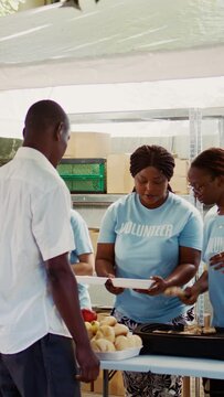 Vertical video Youthful volunteers contributing to hunger alleviation through the provision of hot meals to the underprivileged. Humanitarian aid being provided to the poor, needy and homeless people.