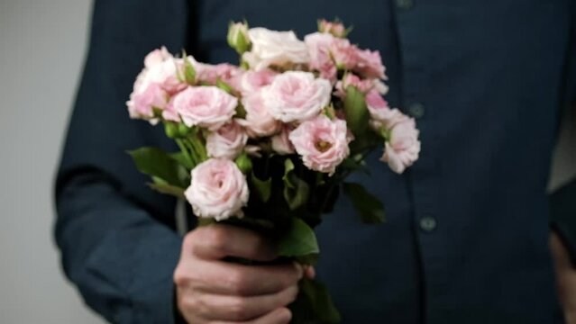 man gives a beautiful bouquet of pink roses. a male hand holds out flowers as a gift. concept of congratulations on Mother's Day, Valentine's Day, Women's Day. selective focus. closeup.