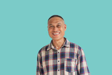 Middle-aged man in his 50s wearing a plaid shirt is smiling happily, isolated on a blue background....