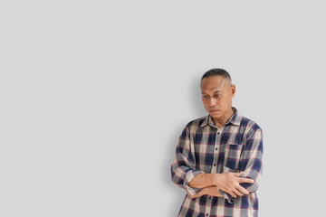 Middle-aged man in his 50s wearing shirt is standing with his arms crossed, worried about various problems, isolated on gray background. Concept of stress at work or problem that come into life.