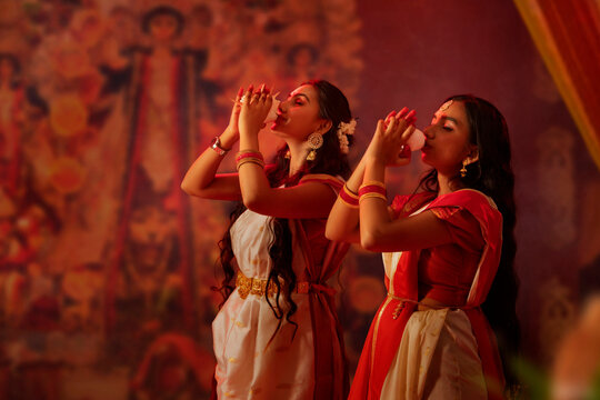 Two Bengali sister playing conch on the occasion of Durga Puja