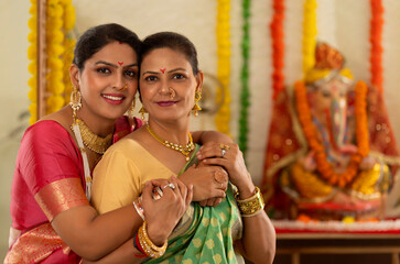 Daughter-in-law embracing her mother-in-law in front of Ganesh idol