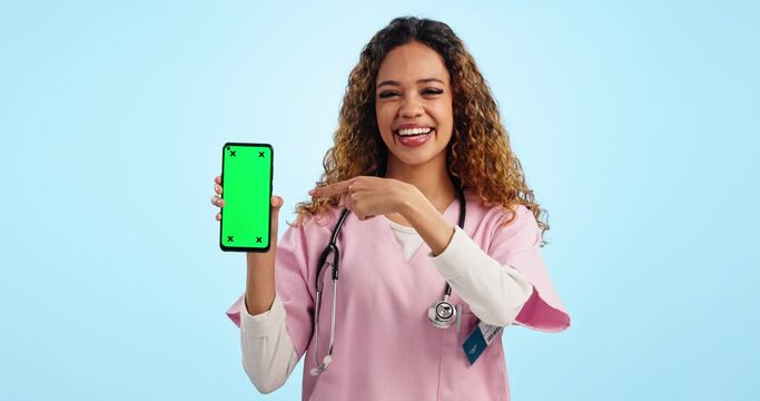 Happy woman, doctor and pointing at green screen phone in studio for advice with tracking marker. Portrait, telehealth and nurse with smartphone chromakey, feedback or website on blue background.