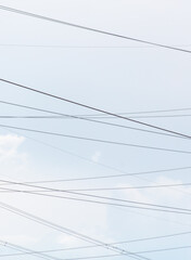 Electrical wires against a gray sky with clouds