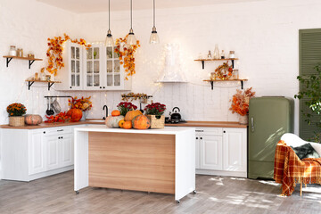 Autumn kitchen interior. Red and yellow leaves and flowers in the vase and pumpkin on light background