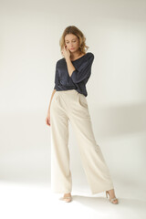 Serie of studio photos of young female model wearing simple beautiful outfit, silk satin blouse and...