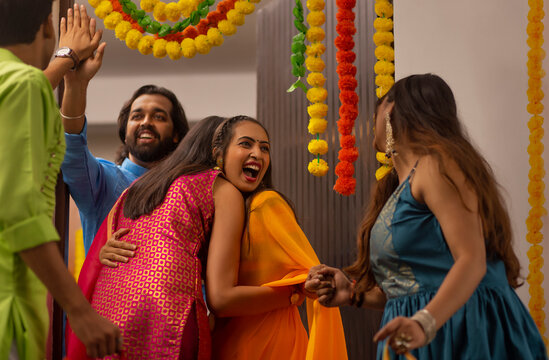 Cheerful excited and surprised couple welcoming and greeting friends  during  Diwali celebrations  at the entrance of their own home 