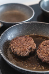 Juicy ground beef hamburger patty sizzling and cooking to perfection inside a frying pan