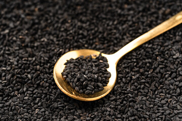Black cumin seeds on golden spoon macro photography