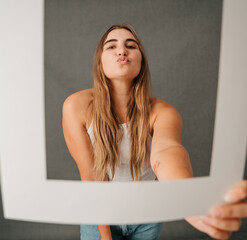 Young female blowing a kiss posing with picture frame