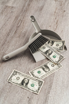 Dustpan and brush alongside scattered one-dollar bills on the floor