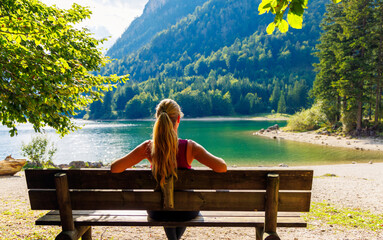 Woman sitting on bench looking at lake landscape- travel,freedom,tourism,relax concept