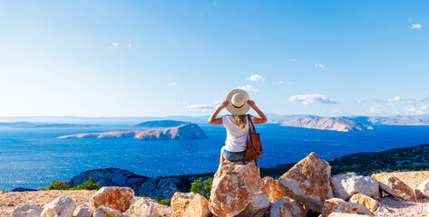 Woman sitting on rock enjoying panoramic view of sea and islands- travel, vacation,adventure, tourism concept