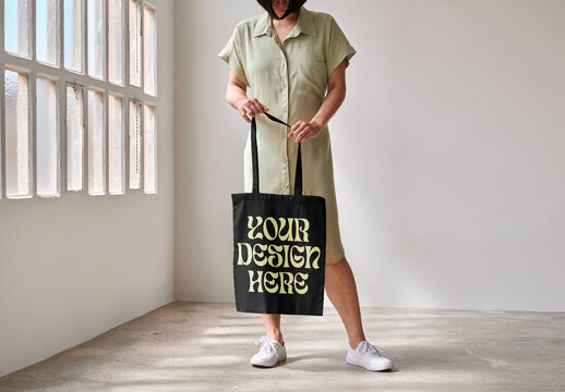 Mockup of woman holding customizable tote bag, low section