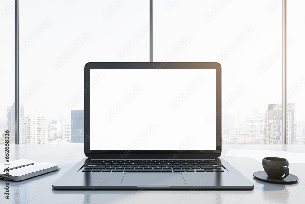 Poster close up of modern workplace with empty white mock up laptop screen, supplies, coffee cup and panora