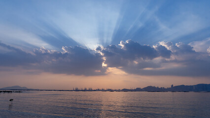 huge white sun-rays behind cloud, calm peach pink blue sky 