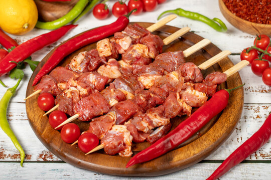 Lamb skewers on wood background. Raw lamb skewer with herbs and spices. Local name kuzu kusleme. Close up