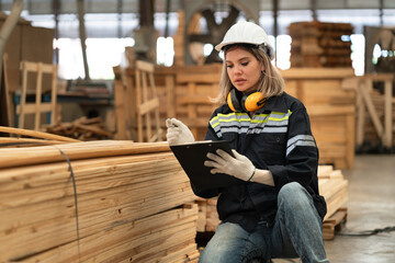 Caucasian technician craft woman holding clipboard with stock timber background at wood factory	