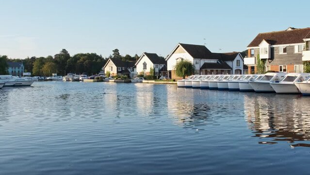 . Low down view of rental properties and hire boats on the River Bure in Wroxham in the heart of the Norfolk Broads. Captured early morning at sunrise