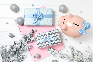 Piggy bank, gift boxes, notepad and fir branches on white background, top view