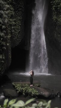 Brunette girl posing against the background of a waterfall