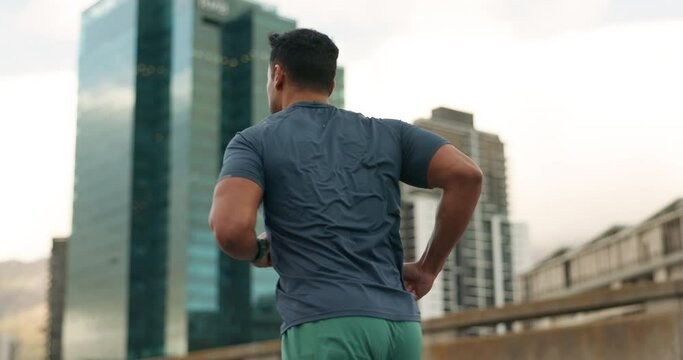 Running, fitness and man with watch in city for marathon training, exercise and cardio workout. Sports, runner and back of person in road check time for performance speed, endurance and wellness