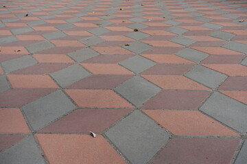 Geometric pavement made of grey, coral red and maroon concrete tiles