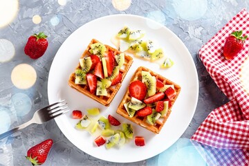  Belgian waffles with fruits strawberries and kiwi on white plate closeup. Tasty healthy breakfast