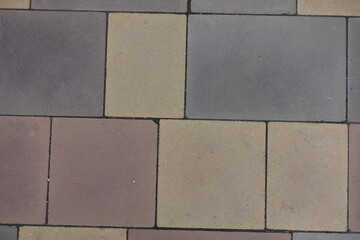 Macro of pavement made of pink, yellow, brown and grey concrete blocks