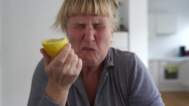 woman bites ripe lemon and makes face