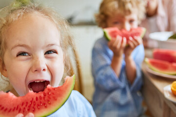 Blond girl shouting while eating watermelon