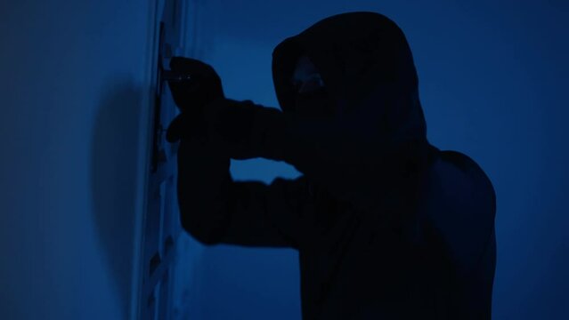 Thief opening door with lock picker.