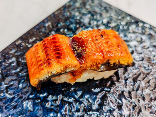 Eel rice sushi is on a plate ready to eat. "Unagi Sushi" is a popular type of sushi in Japanese cuisine. The eel is often cooked until it becomes tender and slightly crispy on the outside by grilling.