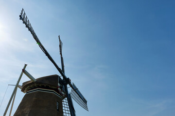 Closeup of the four wings of a traditional thatched dutch windmil in Hantum Friesland in silhouette against a blue sky. The windmill was build is 1880 for the drainage of the polder