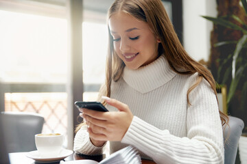 Woman using phone and drinking coffee.