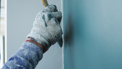 A worker is painting the walls of the house with a primer using a paint roller.