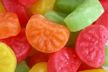 mixed fruit sugar syrup candies on white background, orange candies 