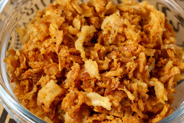 Crispy fried onions in bowl, a pile of freshly chopped onions