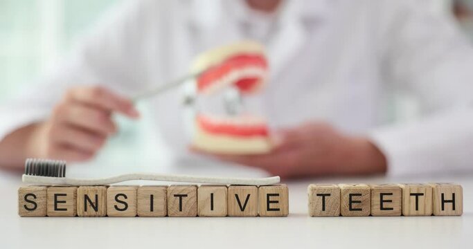 Dentist cleans teeth of artificial jaw model. Increased sensitivity of teeth rationale and treatment