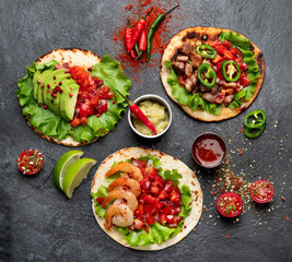 Tacos with salsa, vegetables and avocado on black background