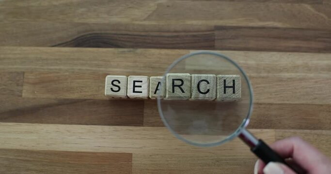 Search for words on wooden cubes with magnifying glass on table. Search for information, creative ideas and the meaning of life
