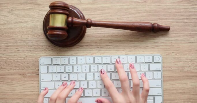 Judge hands working with computer keyboard at wooden table top view. Cybercrime and judgment