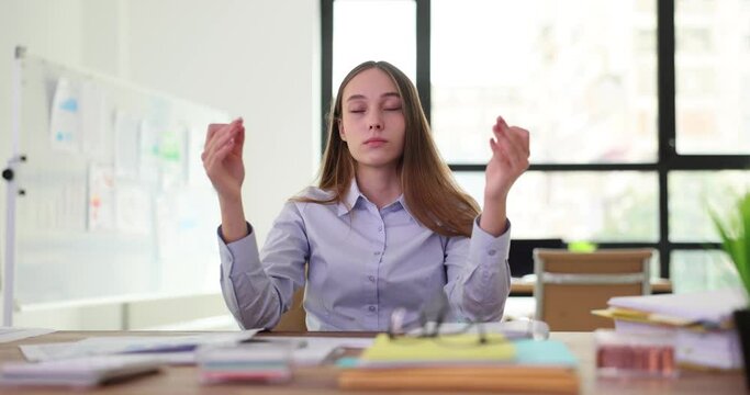 Calm woman relaxes meditating at workplace. Manager without stress at work attentive peaceful young businesswoman or student
