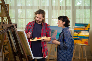 Closeup to the camera attractive couple artist have a fun time together spending in the studio they...