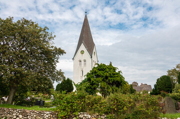 Fototapeta na wymiar Der Friedhof von Nebel auf der Nordeseeinsel Amrum mit der markanten Kirche und Kirchturm